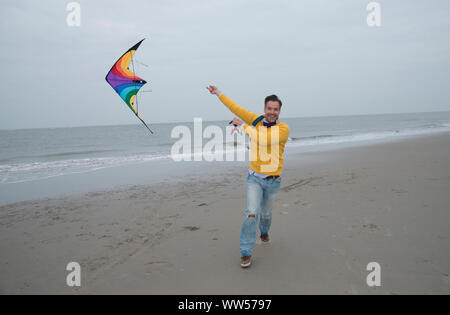 Uomo che corre sulla spiaggia volare un kite Foto Stock