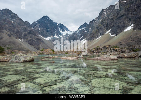 Laghetto prima del lago Blåvatnet con massa strutturato sott'acqua in primo piano e alpi Lyngen in background, Lyngen, Norvegia Foto Stock