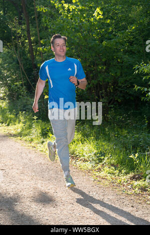 Uomo in abiti sportivi jogging nel bosco Foto Stock