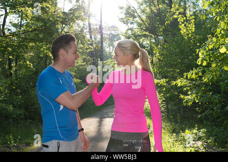 Matura in sportswear nella foresta, tenendo le mani Foto Stock