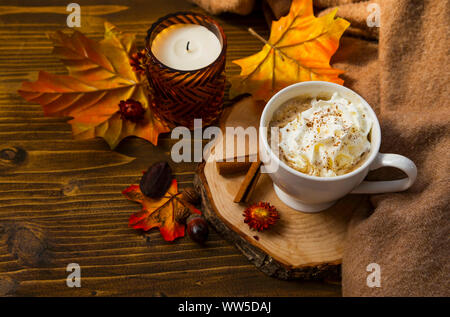Zucca piccante latte con panna montata e coppa maglione. Autunno tazza da caffè con zucca e cannella spice sul tavolo di legno con l'autunno di candela e decorat Foto Stock