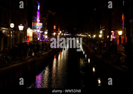 I turisti, lanterne rosse e le luci al neon si riflettono sulla superficie di un canale nel quartiere a luci rosse di Amsterdam, Foto Stock