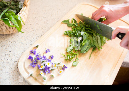 Il taglio di erbe e fiori su tavola di legno con il coltello Foto Stock