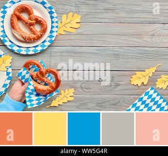 Corrispondenza di colore dalla tavolozza Oktoberfest cibo foto con mano azienda pretzel e di colore bianco-blu decorazioni Foto Stock