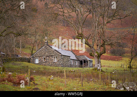 Un tradizionale cottage in pietra circondato da vecchi tress nel cuore del Distretto dei Laghi Inglesi su un giorno inverni. Foto Stock