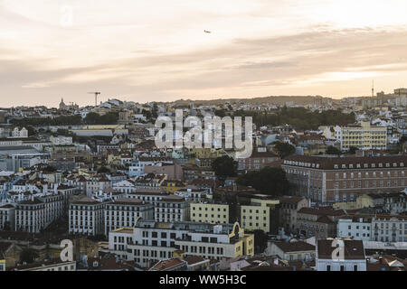 Vista panoramica di Lisbona case con tegole rosse dal castello Sao Jorge al tramonto, un aeroplano è volare oltre al background, turisti spot in P Foto Stock