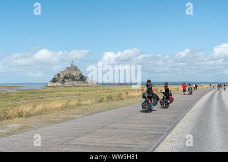 Le Mont Saint Michel, Manche / Francia - 18 agosto 2019: a lunga distanza turisti in bicicletta visitando e viaggiano verso il famoso Mont Saint Michel in nord Foto Stock