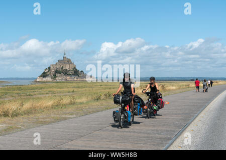 Le Mont Saint Michel, Manche / Francia - 18 agosto 2019: a lunga distanza turisti in bicicletta visitando e viaggiano verso il famoso Mont Saint Michel in nord Foto Stock