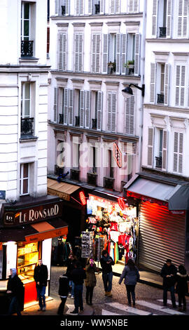 Pedoni di fronte a una barra illuminata in una strada laterale del quartiere Montmartre di Parigi, Foto Stock