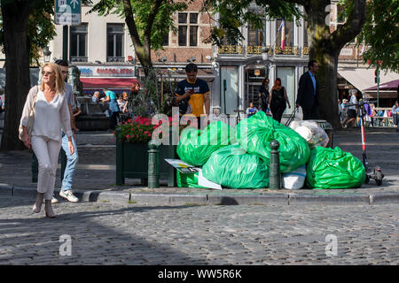 Una pila di sacchi della spazzatura di domestici e rifiuti commerciali su una piazza centrale a Bruxelles, come i passanti da guardare lontano Foto Stock