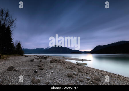 Barca a remi sulla riva del Walchensee poco dopo il tramonto e sullo sfondo la Monaco di Baviera backyard montagne Herzogstand, Heimgarten e Jochberg Foto Stock