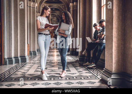 Vita del Collegio.Bella studenti insieme permanente e chattare su l'università hall. Foto Stock