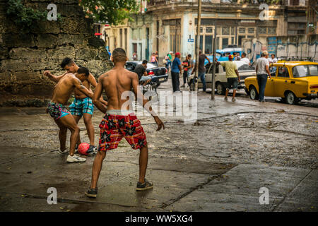 Giovani uomini che giocano a calcio per strada, Havana, Cuba Foto Stock