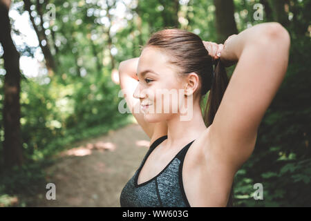 Ritratto di sorridente donna sportivo preparare i capelli per l'esecuzione. Pronto per l'esecuzione. Foto Stock