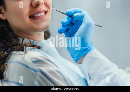 Close up della donna avente controllo odontoiatria fino in studio dentistico. Dentista esaminando una denti del paziente con strumenti dentali. Odontoiatria. Foto Stock