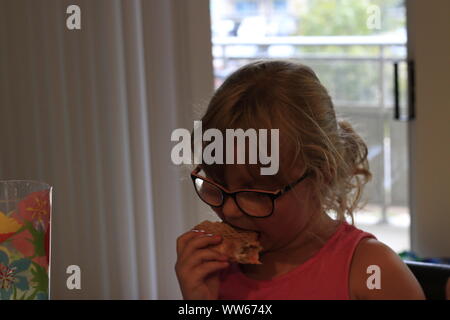 Bambina mangia il calzone al concetto di contatore di pasti in famiglia Foto Stock