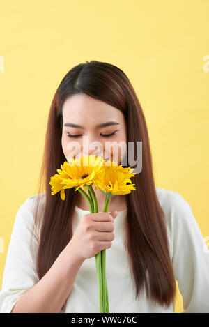 Giovane donna odore di girasoli su sfondo giallo Foto Stock