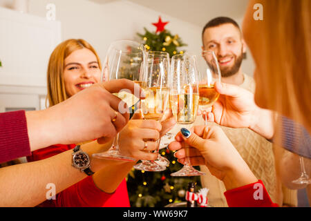 Chiudere la vista immagine che mostra un gruppo di amici per celebrare il nuovo anno, tenendo i bicchieri con lo champagne tintinnio tra di loro. Albero di natale sullo sfondo Foto Stock