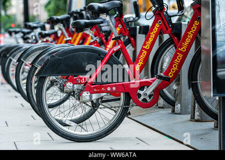 Washington DC, Stati Uniti d'America - 9 Giugno 2019: fila di biciclette rosso utilizzato nella capitale programma Bikeshare appoggiato sul fianco a piedi Foto Stock