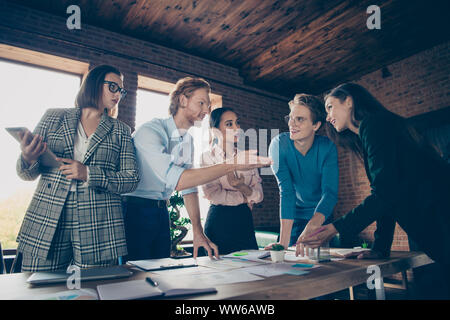 Close up photo stand attorno al tavolo di gioco la gente di affari ha il suo egli lui la sua mostra documenti documenti fogli di spiegare parlare raccontare la strategia di sviluppo degli investimenti Foto Stock