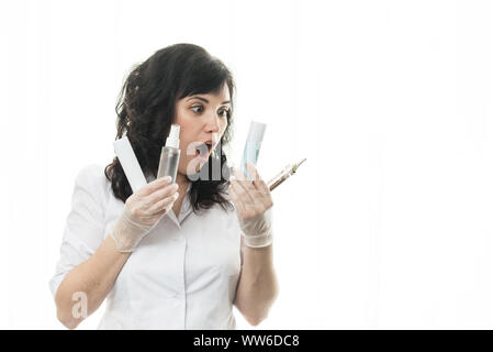 La donna mantiene i tubi con cosmetici nelle sue mani. Ragazza isolato con un'emozione di sorpresa. Mani con bottiglie di cosmetici Foto Stock