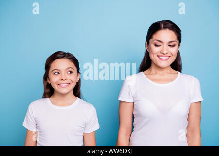 Close up foto incredibili piuttosto due persone dai capelli marroni mamma e figlia piccola in piedi dritto sul lato cercando ogni altra astuzia indossando bianca t-shirts Foto Stock