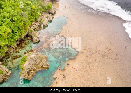 Piscine naturali sulla spiaggia rocciosa con turisti formata con la bassa marea. Magpupungko piscine naturali di roccia. Siargao, Filippine. Foto Stock