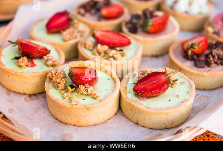 Riempito di sfondo con colorate torte e dessert con frutta fresca. Assortiti mini diverse torte con crema di cioccolato e frutti di bosco. Foto Stock