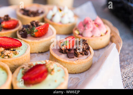 Riempito di sfondo con colorate torte e dessert con frutta fresca. Assortiti mini diverse torte con crema di cioccolato e frutti di bosco. Foto Stock