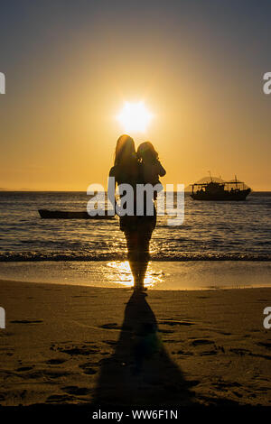 Silhouette di una donna in piedi sulla spiaggia portando la sua figlia, Brasile