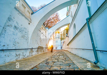 I monaci di Kiev Pechersk Lavra Cave Monastery vanno alla Cattedrale della Dormizione con una vista sul tramonto del sole e sui luminosi alberi autunnali a Kiev, Ucraina Foto Stock