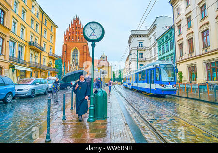 Cracovia in Polonia - Giugno 13, 2018: La suora sotto ombrellone passeggiate in tutti i Santi Piazza della Santissima Trinità Basilica, il 13 giugno a Cracovia Foto Stock