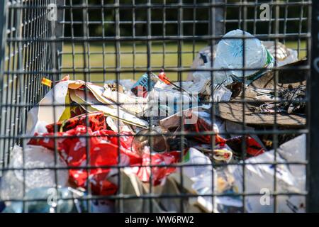 Dettaglio del cestino dei rifiuti / Bin riempito principalmente con immondizia di plastica nel parco pubblico Hasenheide a Berlino. Foto Stock