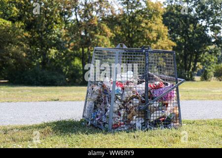 Berlino, Germania - 11 settembre 2019: Cestino pieno può / bidone dei rifiuti nel parco pubblico Hasenheide a Berlino. Riempito principalmente con immondizia di plastica Foto Stock