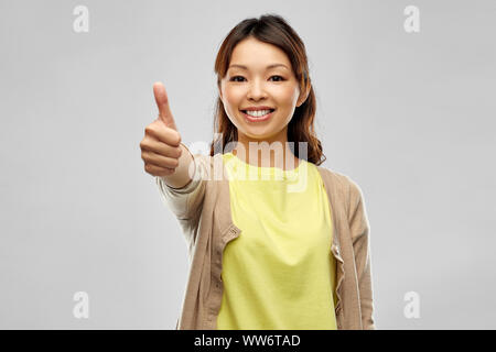 Felice donna asiatica che mostra pollice in alto Foto Stock