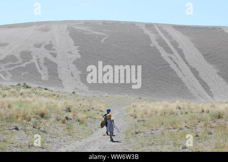 I due ragazzi che indossa caschi e trasportano i loro commissioni per andare sandboarding in Bruneau, Idaho Foto Stock