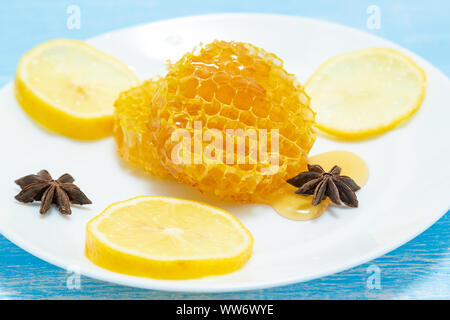 Round favi, limone e anice giacciono su una piastra su uno sfondo blu. Foto Stock