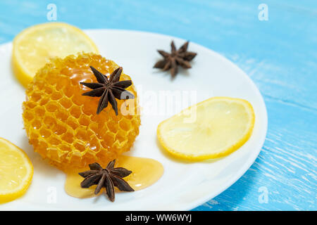 Round favi, limone e anice giacciono su una piastra su uno sfondo blu. Foto Stock