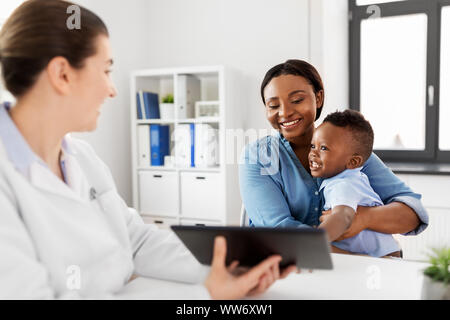 Madre con bambino e medico con una compressa alla clinica Foto Stock