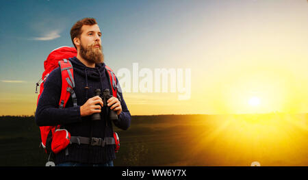 Uomo con zaino e binocolo su sunset Foto Stock