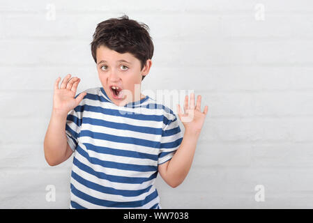 Bambino sorpreso facendo una grimace su Sfondo mattone Foto Stock