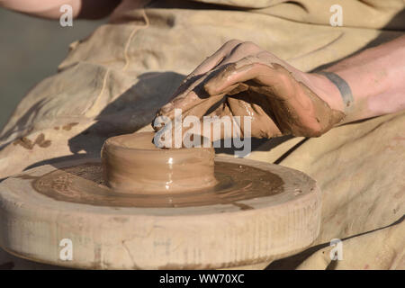 Ceramica ceramista maschio crea un fatto a mano prodotto di creta. Processo di rotazione della ruota di vasai, mani del ceramista. Foto Stock