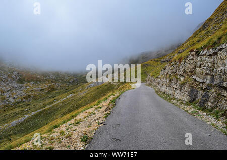 Montagna stretta strada asfaltata, avvolgimento e pericoloso, portando a nuvole basse Foto Stock