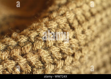 Extreme close up colore ocra naturale a maglia maglione di lana texture, pieghe ondulate, il fuoco selettivo Foto Stock