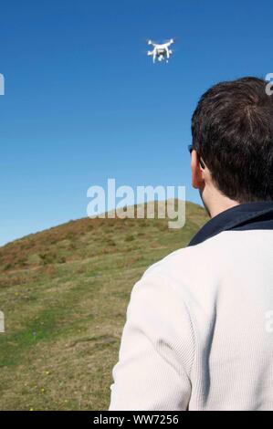 La mezza età uomo alla guida di un drone in montagna Foto Stock