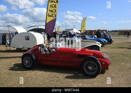 I visitatori in occasione di un evento guardando un AC Cobra Kit anglo-americano auto e altri veicoli sul display nel Kent, Regno Unito. Estate 2019. Foto Stock