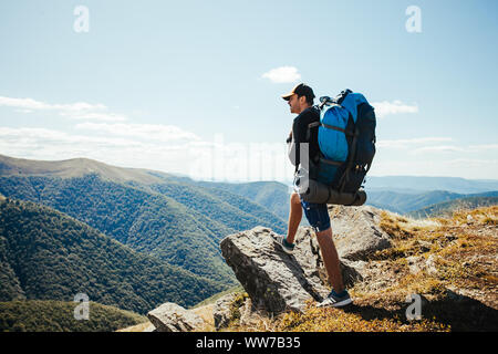 Giovane uomo con zaino in piedi sulla cima della montagna Foto Stock