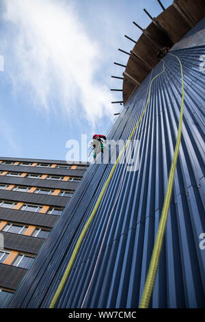 Climber di facciata salendo la torre chirurgica della clinica di Innsbruck in Tirolo, Austria Foto Stock