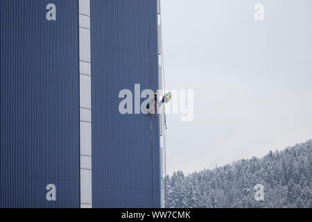 Climber di facciata salendo la torre chirurgica della clinica di Innsbruck in Tirolo, Austria Foto Stock