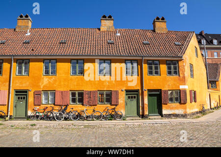 Centro storico di Riga case giallo nel quartiere Nyboder a Copenaghen, un ex quartiere navale con le bici nella parte anteriore del case Foto Stock